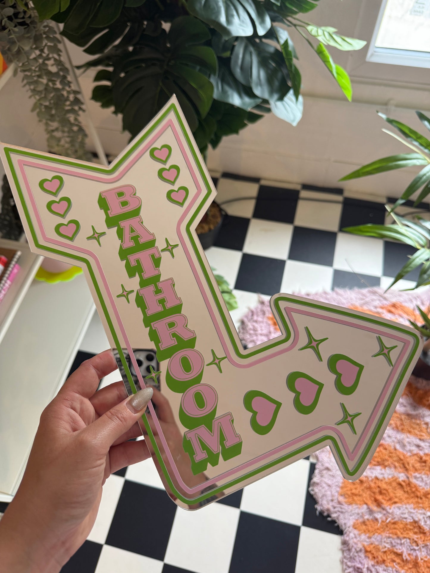 A hand is holding a pink and green arrow-shaped sign with the word "MOMO" written on it.