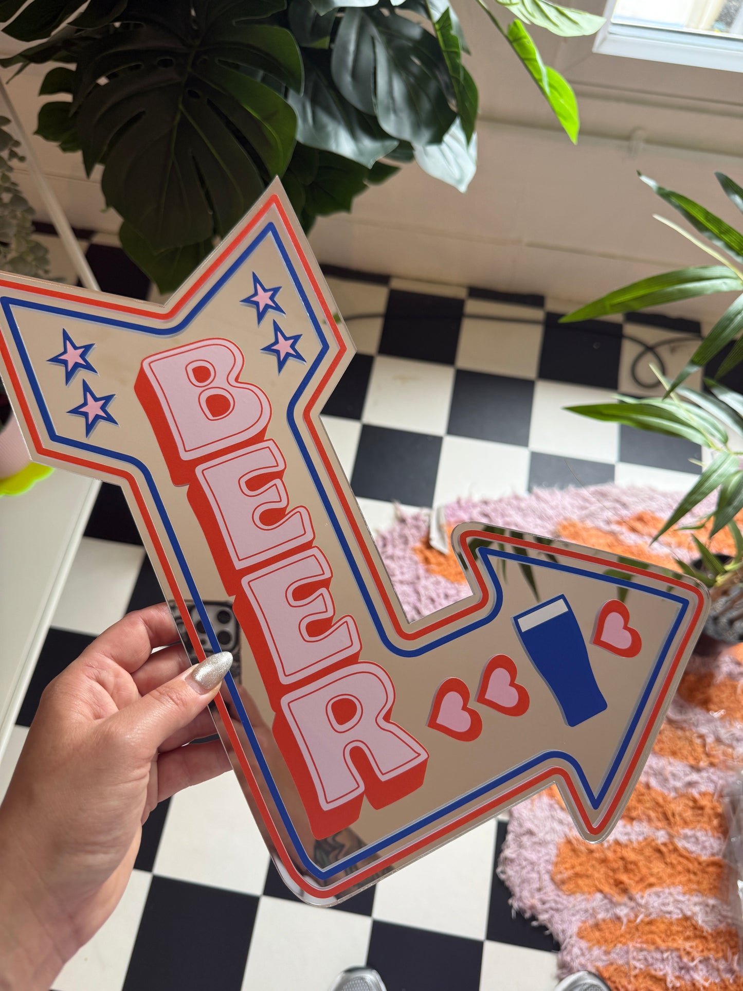 A hand is holding a large sign with a red, white, and blue design, featuring a heart and star pattern.
