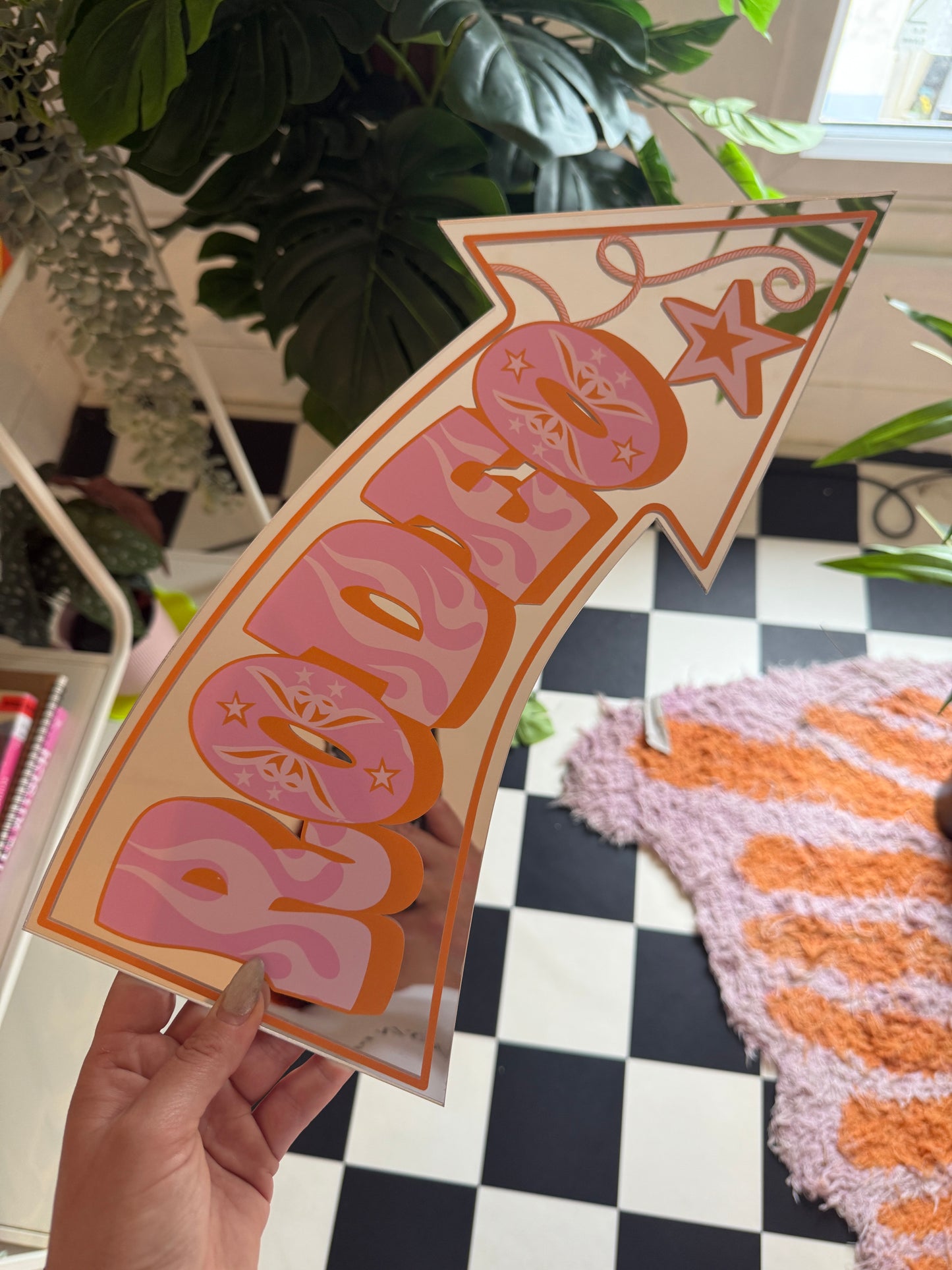 A hand is holding a sign with a pink and orange design, featuring a star and the word "POP" written on it.