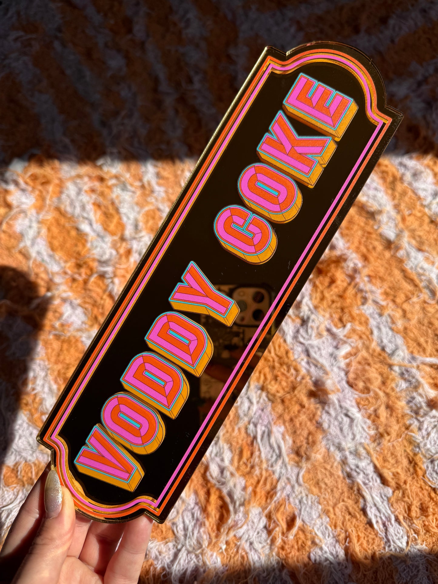 A hand holding a sign with the text "VOODAY VOODAY" in a bold, colorful font.