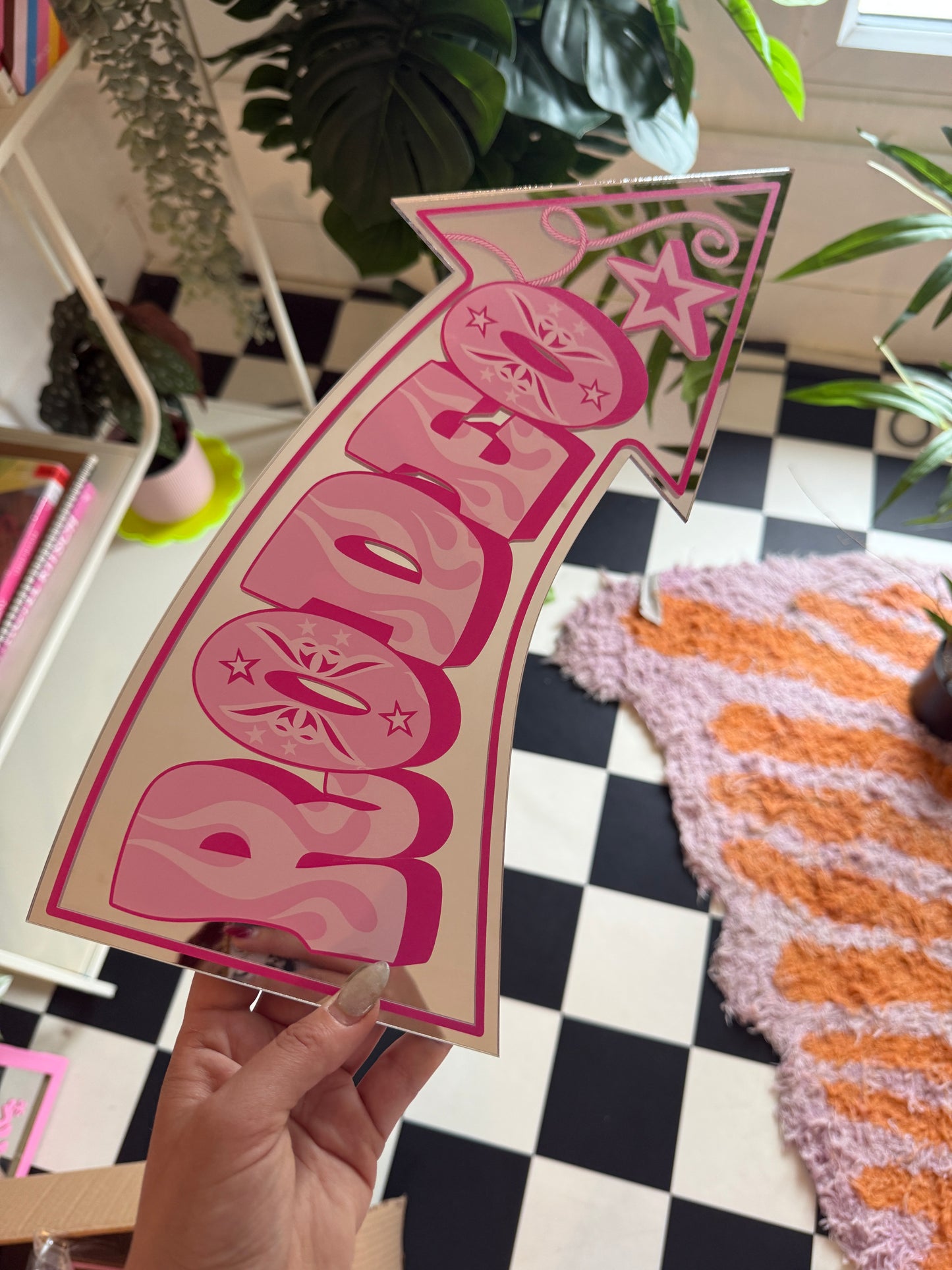 A hand is holding a sign with the word "BOOB" written on it, which is pointing to the left.