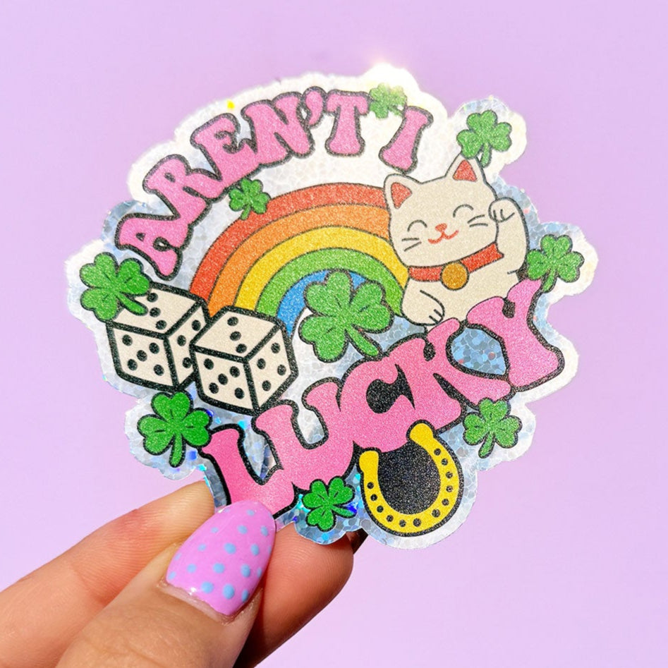 Sticker with rainbow, cat, and text held by a hand on a purple background