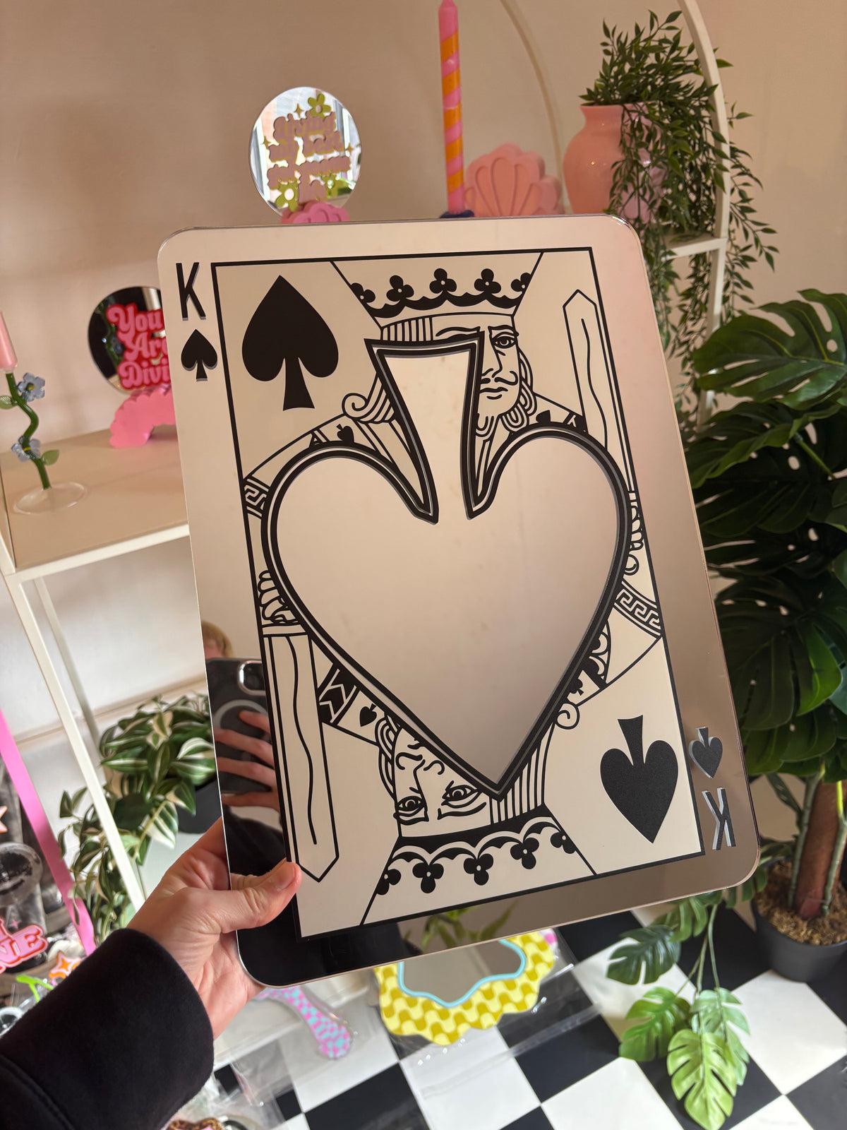 A hand is holding up a large, ornate, and colorful card featuring a large heart shape and various playing card symbols, including spades and a king.