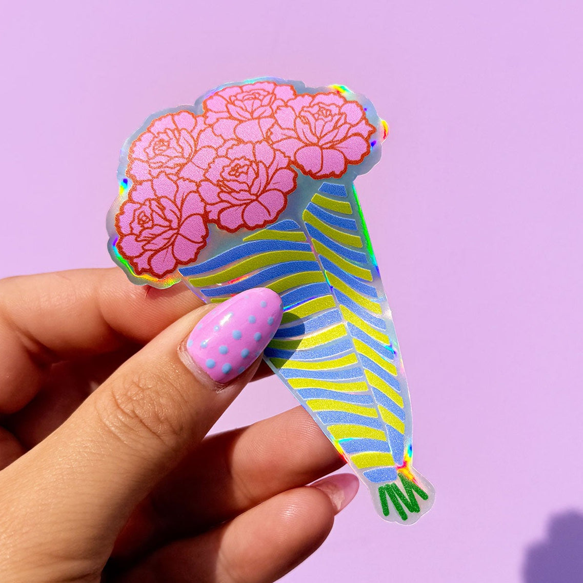 Hand holding a colorful brain-shaped sticker against a purple background