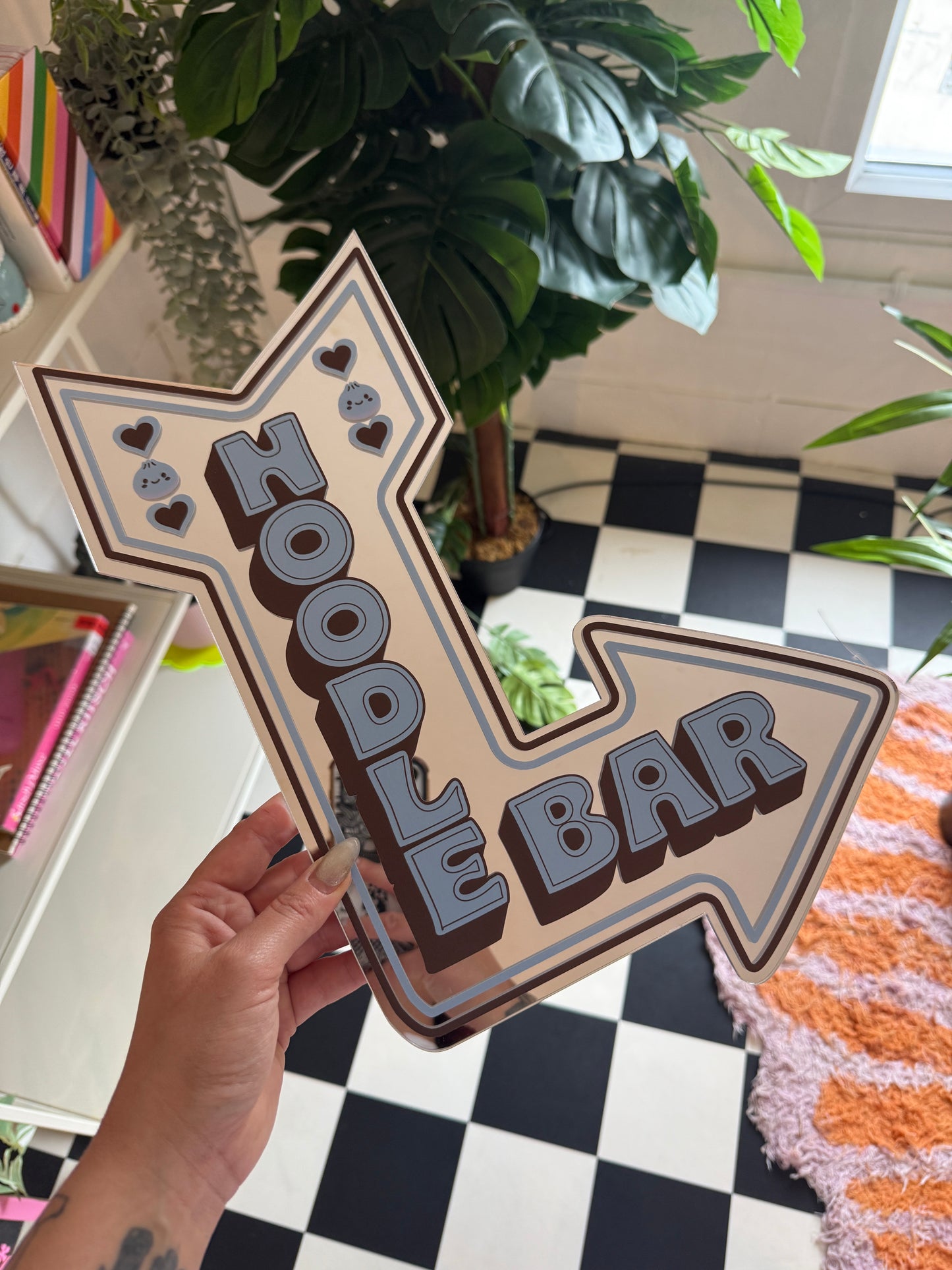 A hand is holding a sign that says "Zoo Bar" in a stylized font, with a decorative arrow design.