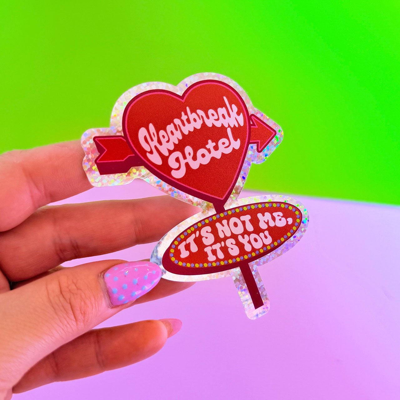 Hand holding two colorful heart-shaped signs with text against a gradient background