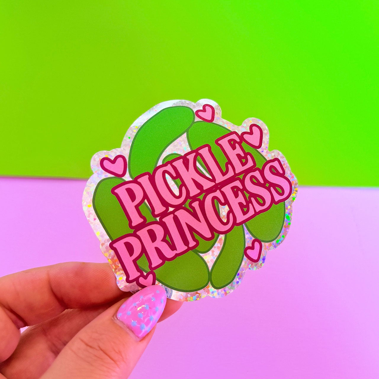 Sticker with 'Pickle Princess' text held by a hand against a colorful background