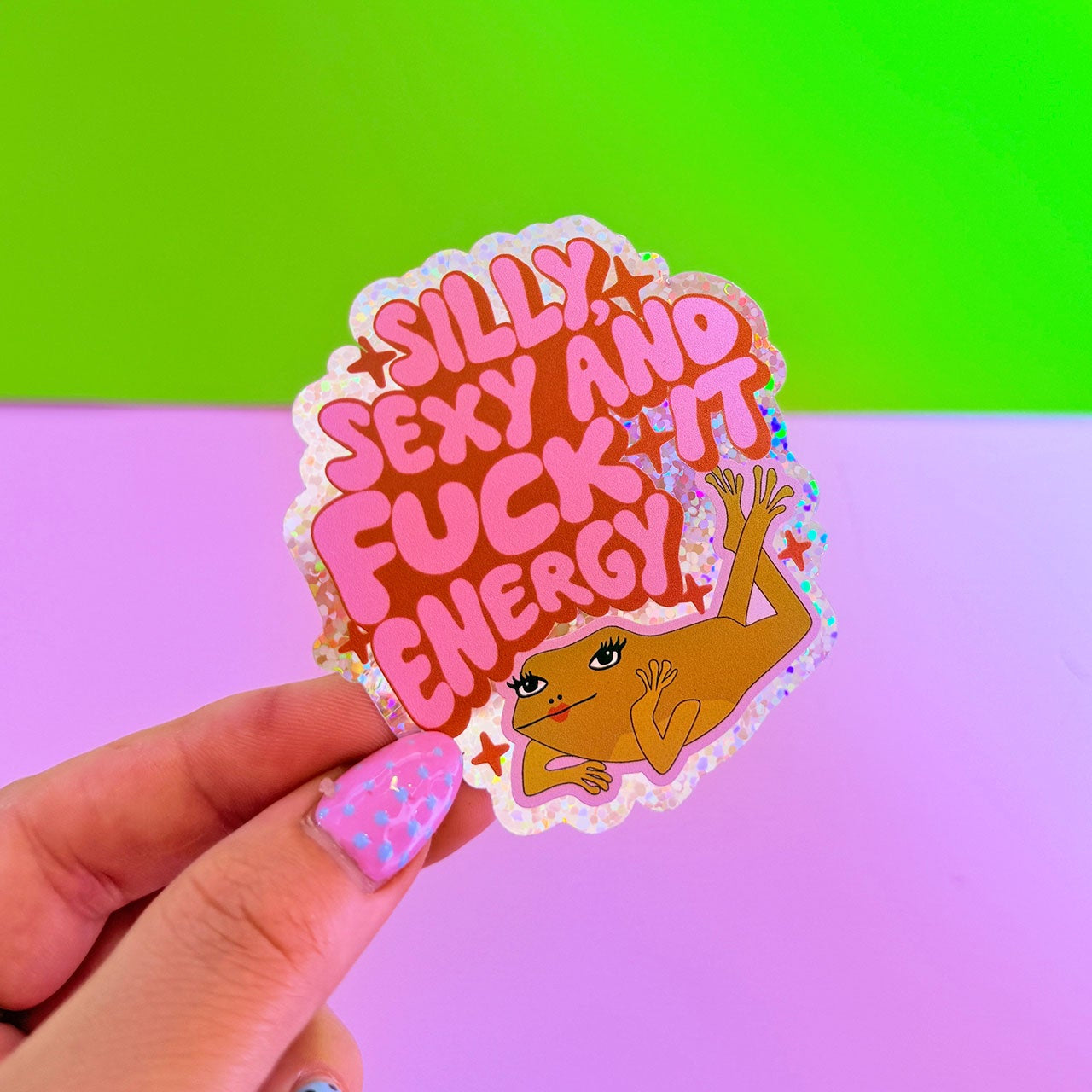 Sticker with text and a graphic held by a hand against a colorful background