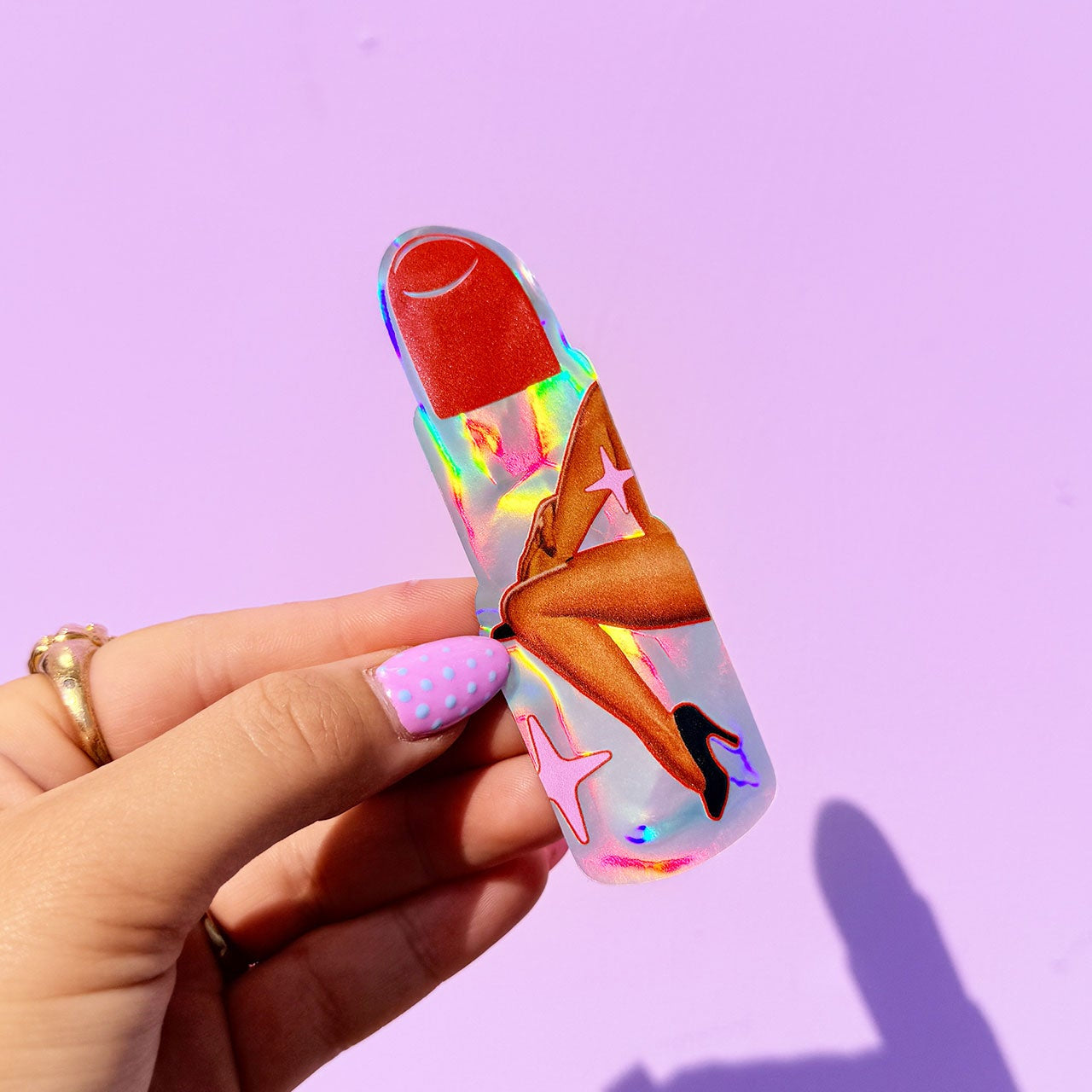 Hand holding a colorful butterfly-shaped object against a purple background