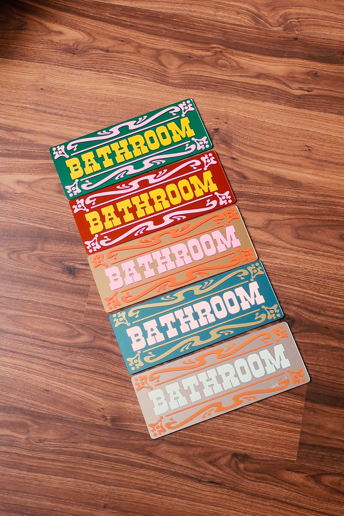 a collection of colorful bathroom signs arranged on a wooden floor.