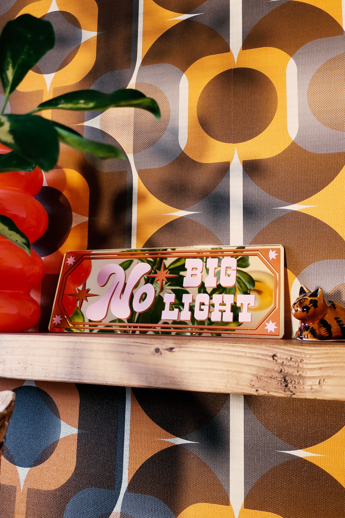 a wooden shelf with a decorative sign that reads "No Big Light". The shelf is set against a vibrant, patterned wall with a retro-style design.