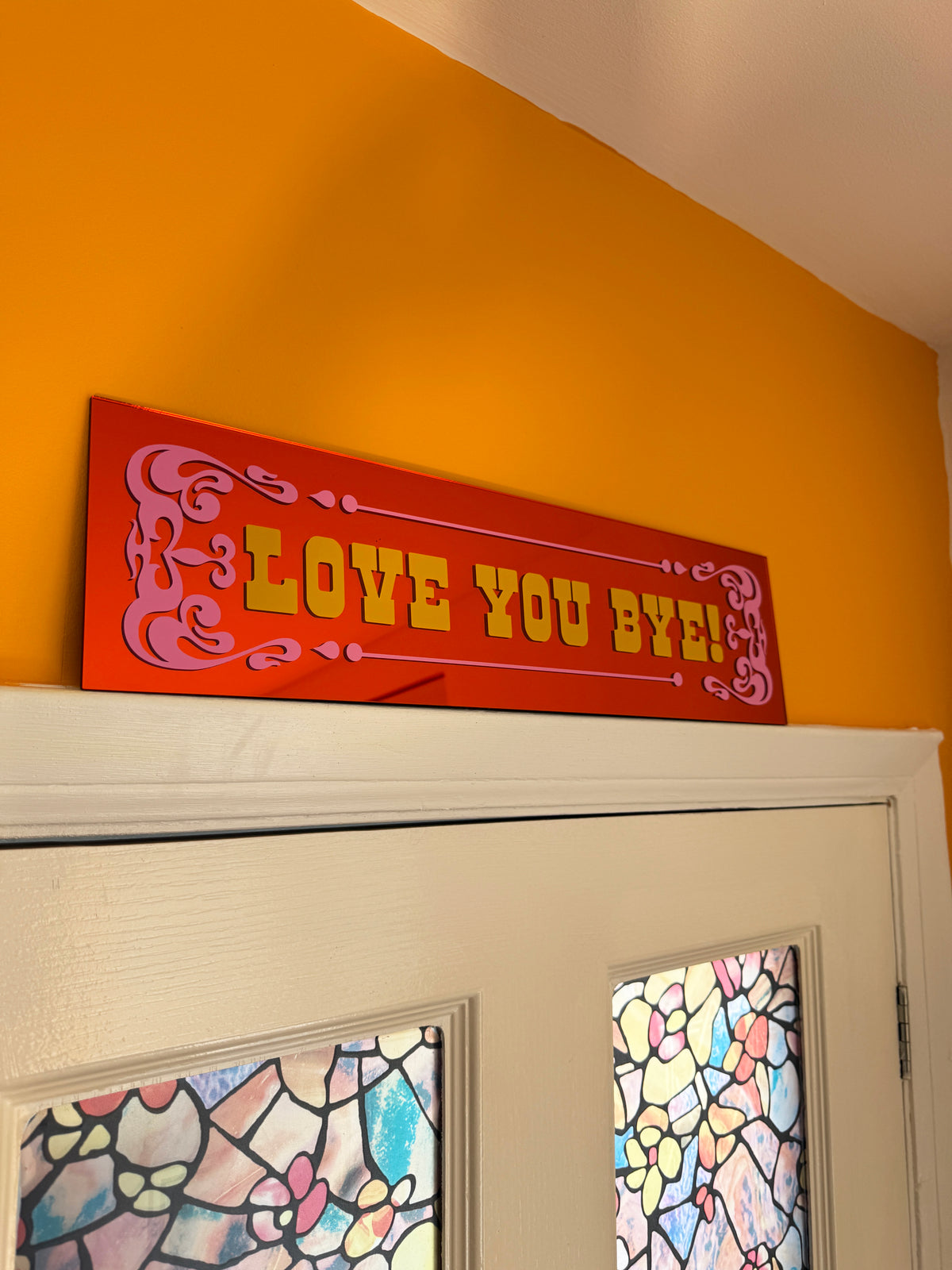 a colorful sign with the text "LOVE YOU BYE" displayed on a door.