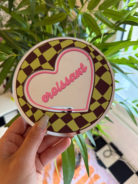 A hand holding a heart-shaped object with a checkered pattern and the word "Sapphires" written on it.