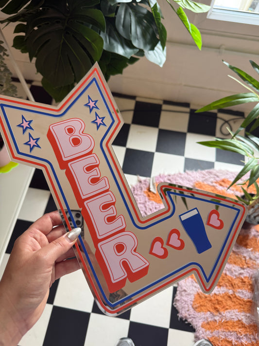 A hand is holding a large sign with a red, white, and blue design, featuring a heart and star pattern.