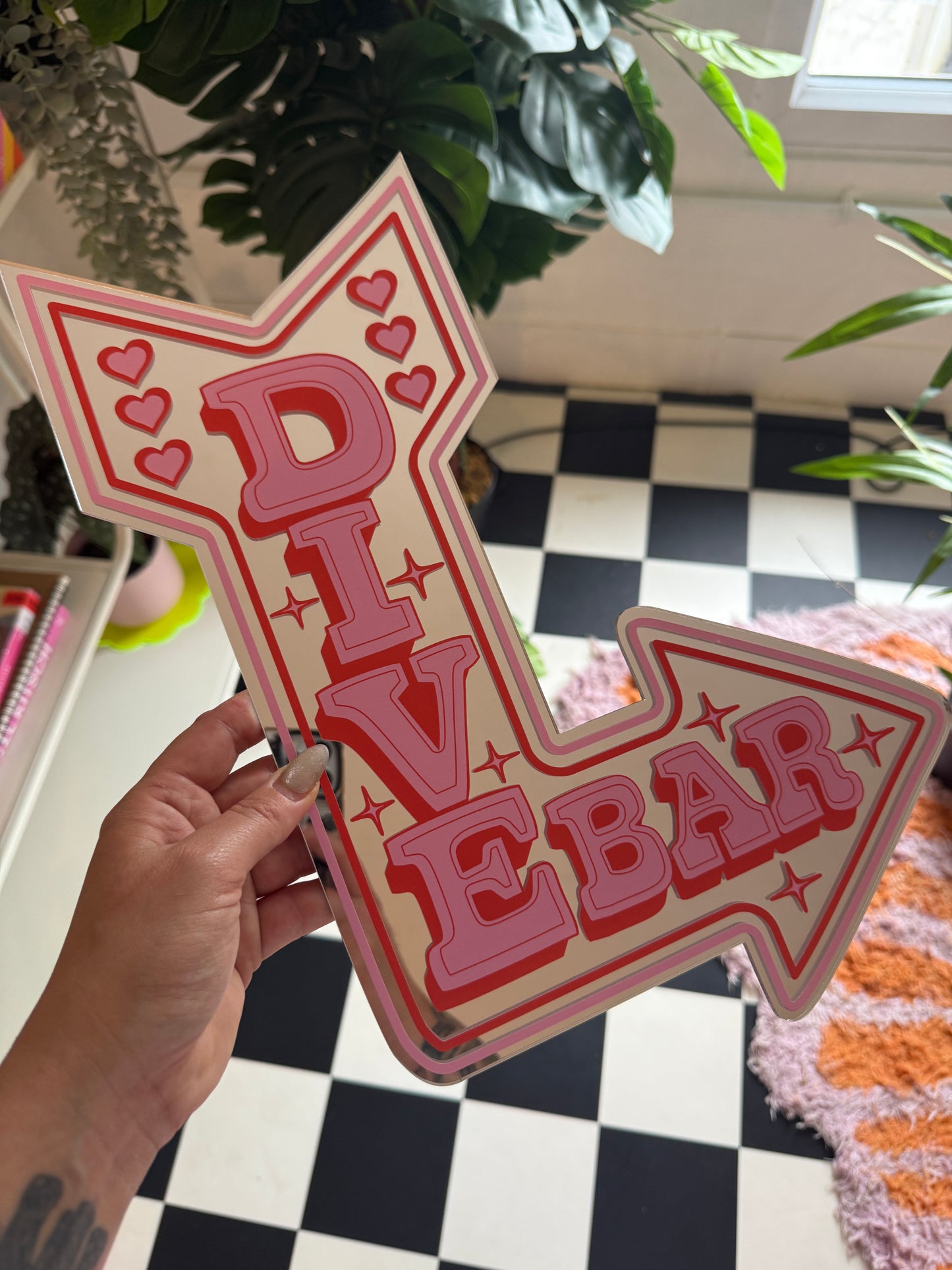 A hand is holding a pink sign with the word "BAR" written on it, which is pointing to the right.