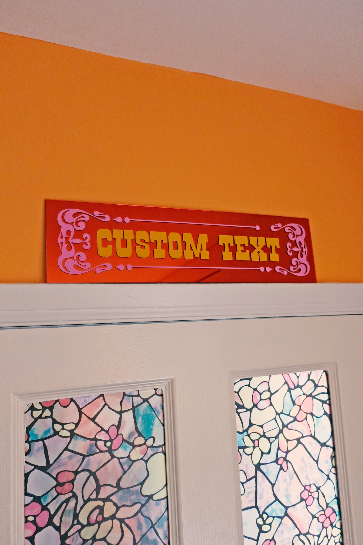 a red sign with the text "CUSTOM TEXT" on it, placed above a door with a stained glass window.