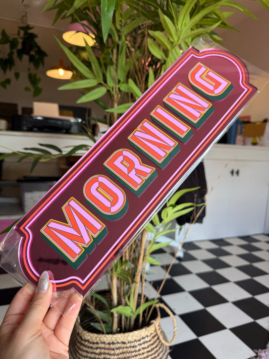 A hand holding a sign with the word "MORNING" written on it.