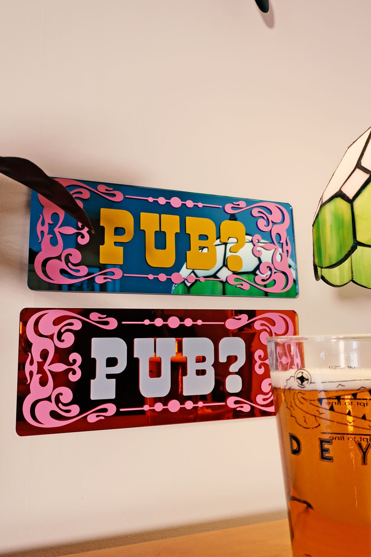 a sign that reads "PUB?" and a glass of beer on a table.