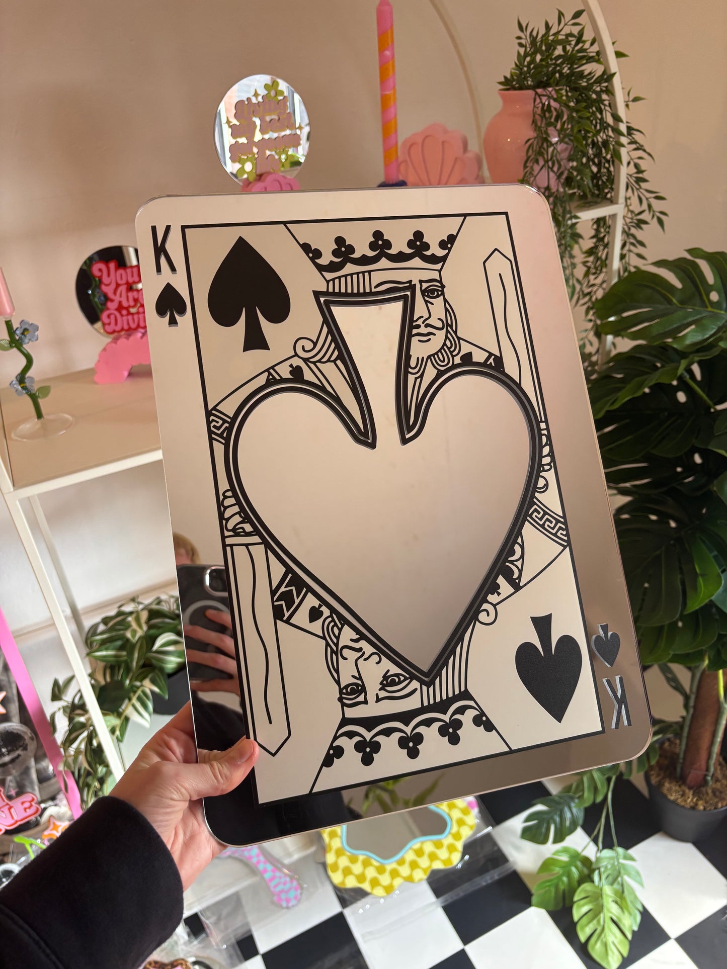 A hand is holding up a large, ornate, and colorful card featuring a large heart shape and various playing card symbols, including spades and a king.