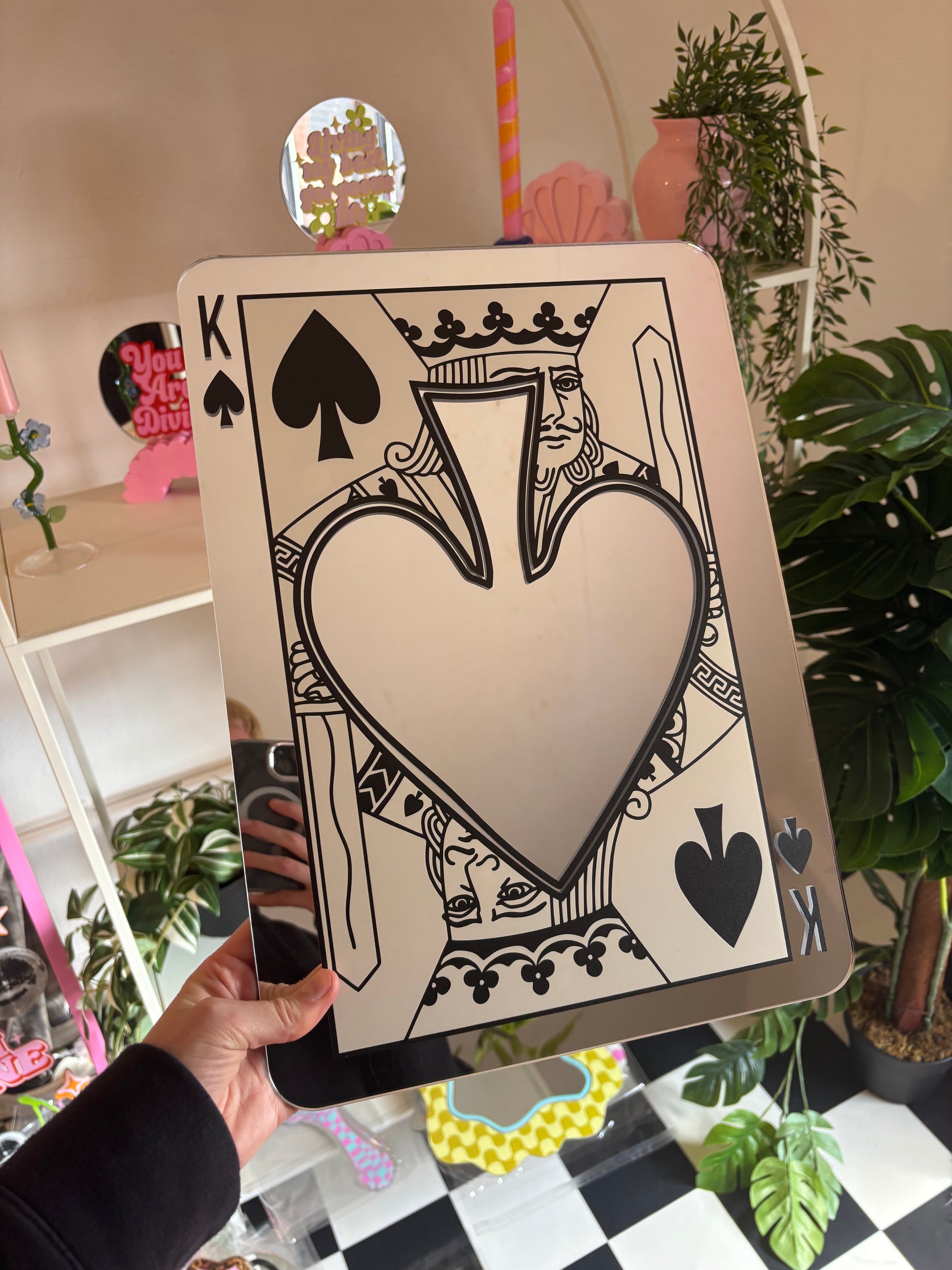 A hand is holding up a large, ornate, and colorful card featuring a large heart shape and various playing card symbols, including spades and a king.