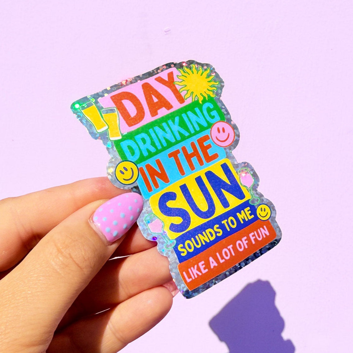 Colorful sticker with text held by a hand against a purple background