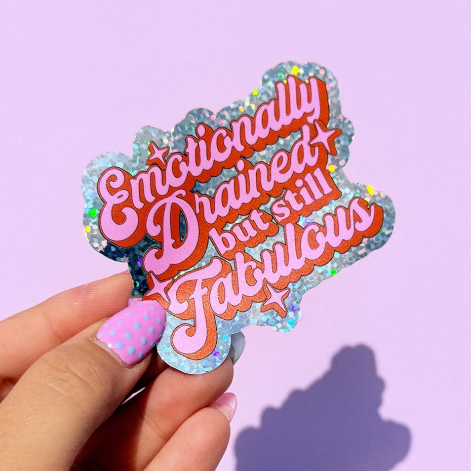 Hand holding a colorful sticker with text against a purple background