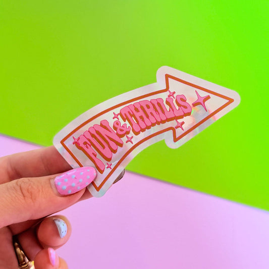 Hand holding a pink and orange 'Fun and Thrills' sign against a green and pink background