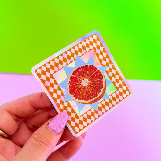 Hand holding a card with a grapefruit illustration against a colorful background