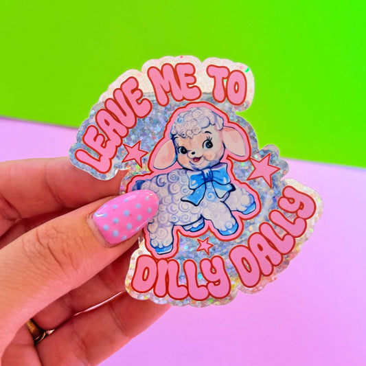 Sticker with cartoon lamb and text held by a hand against a colorful background