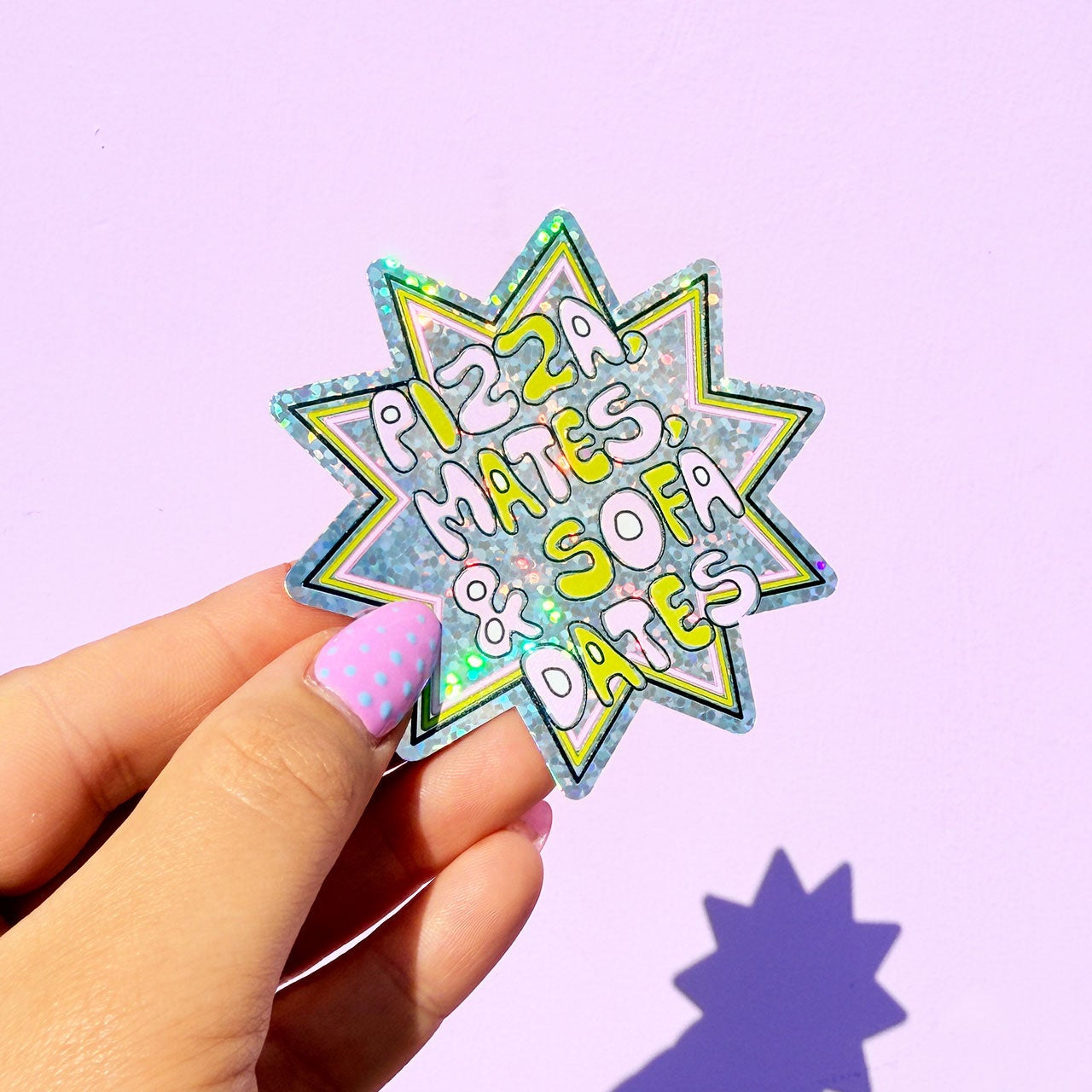 Sticker with 'Pizza Mates, Sofa Dates' text held by a hand against a light purple background