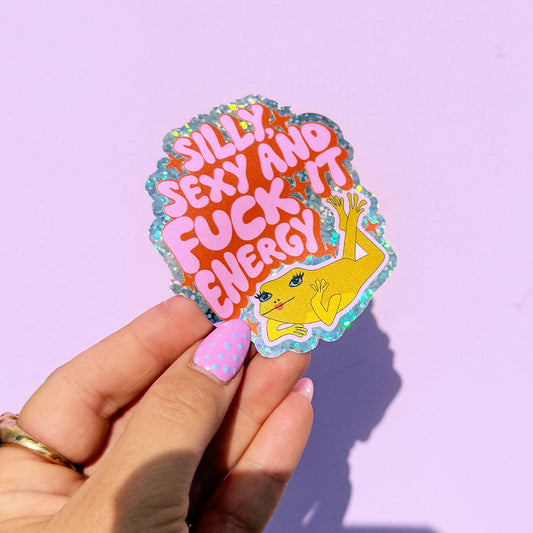 Hand holding a colorful sticker with text against a light purple background