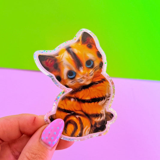 Hand holding a sticker of a tiger cat against a green and purple gradient background