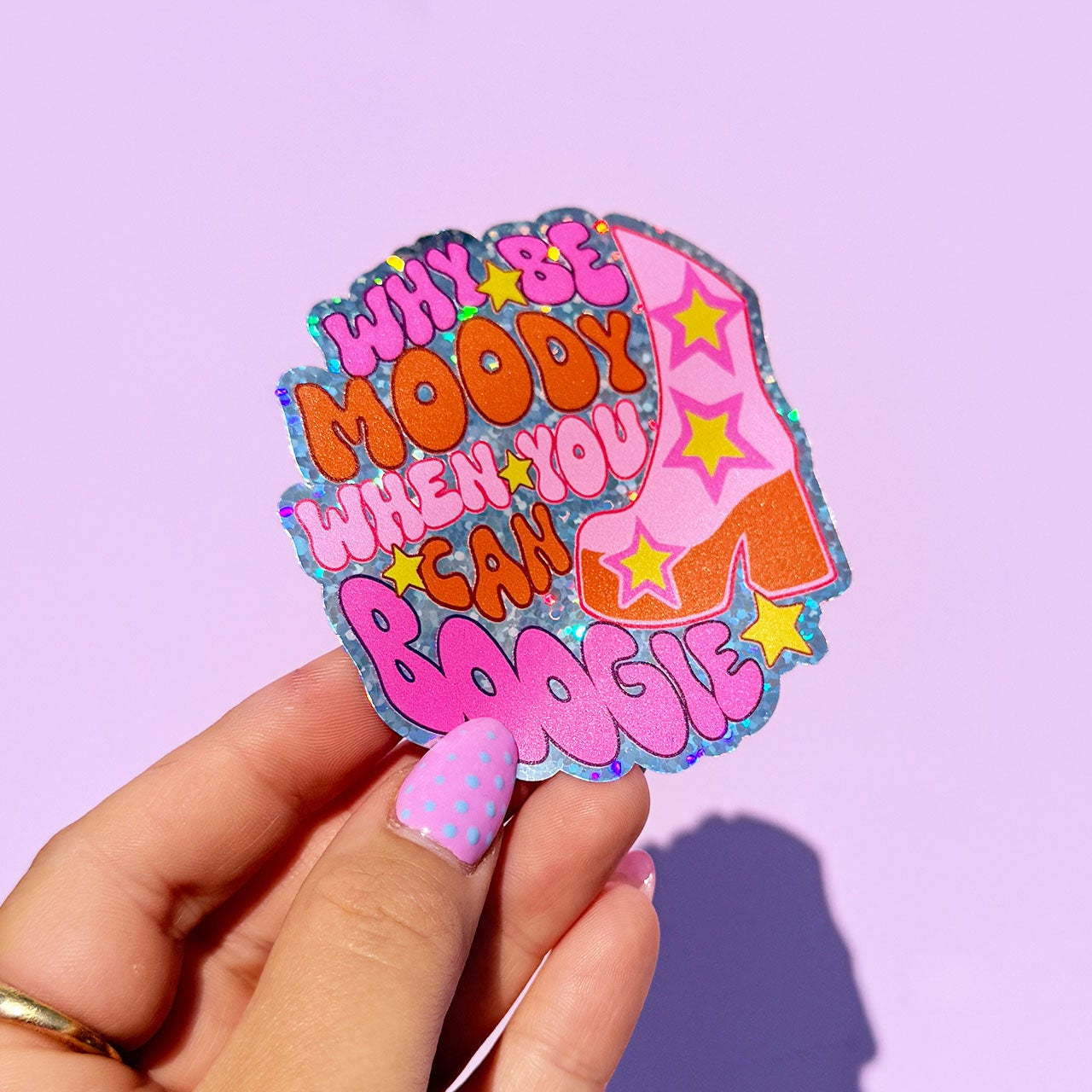 Colorful sticker with text held by a hand against a purple background